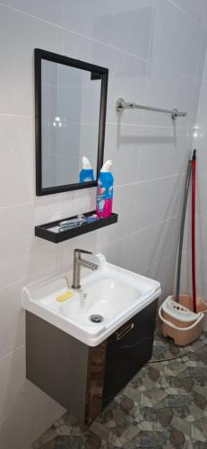 a bathroom with a sink and a mirror and a toilet at D'Intan Villa Gerik in Gerik