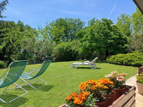two lawn chairs and flowers in a yard at Carmen de Nella Eco Lodge 4* in Caprino Veronese