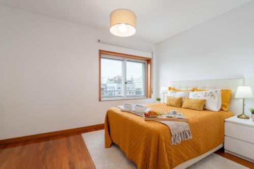 1 dormitorio con cama con colcha de color naranja y ventana en Spacious Escape Near the Beach by Host Wise, en Matosinhos
