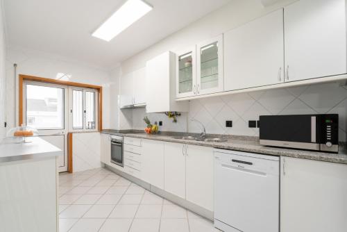 a white kitchen with white cabinets and a microwave at Spacious Escape Near the Beach by Host Wise in Matosinhos