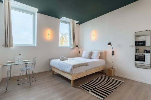 une chambre avec un lit et une table et deux fenêtres dans l'établissement Studio équipé côté rue, parking gratuit, à Villeneuve d'Ascq