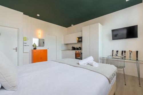 a white bedroom with a large bed and a tv at Studio équipé côté rue, parking gratuit in Villeneuve d'Ascq