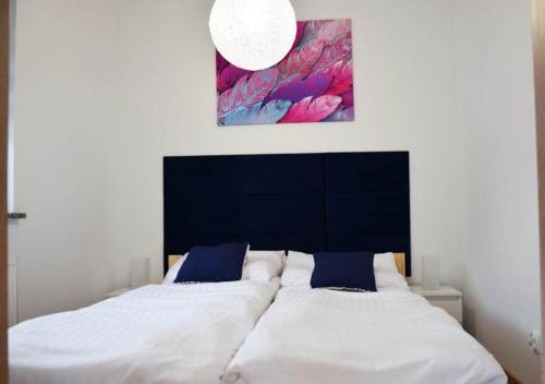 a bedroom with a bed with white sheets and blue pillows at Apartamenty Wakacyjne Historie in Międzylesie