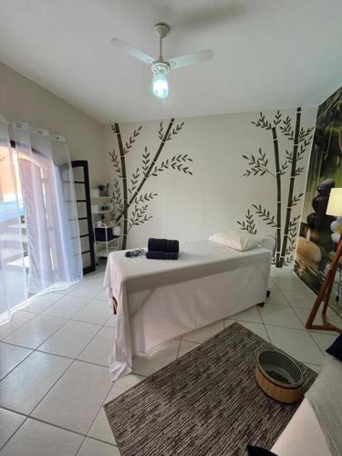 a room with a bed with a table and trees on the wall at Pousada Encantos de Socorro in Socorro