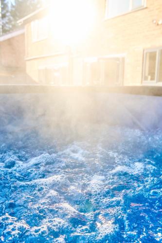 a pool of water with smoke in front of a house at Chic Family Home with Garden Fire Pit & Event Space, Hot Tub in Manchester