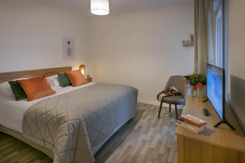 a bedroom with a bed and a desk with a television at DOMITYS LES SEQUANES in Chalon-sur-Saône