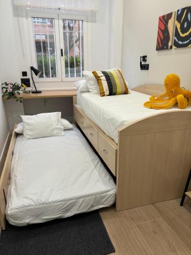 a bedroom with two beds with a teddy bear sitting on top at office 2036 in Tres Cantos