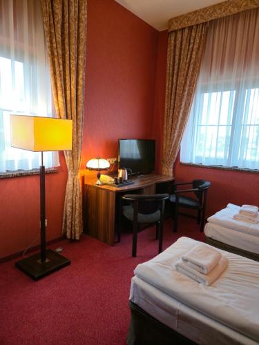 a hotel room with two beds and a desk with a computer at Hotel Dworski Galaktyczny Park in Szczecin