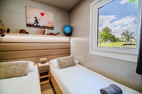 two beds in a small room with a window at DELUXE Lake View Mobile Homes with Thermal Riviera Tickets in Čatež ob Savi