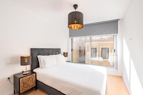a bedroom with a white bed and a window at VIVA Bartolomeu Beach Flats in Porto