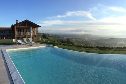a swimming pool with two chairs and a house at Ca'Rapulin in Calosso