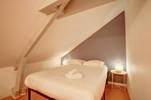 une chambre avec un lit avec des draps blancs et des oreillers dans l'établissement Le Belvédère - Le rendez vous des Copains, à Tours