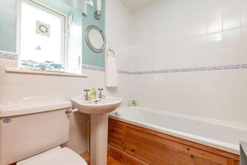 a bathroom with a sink and a tub and a toilet at Smiddy Burn Cottage Kingsbarns in Kingsbarns