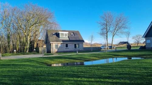 a house on a golf course with a pond at Wiltsangh Bungalow in De Waal
