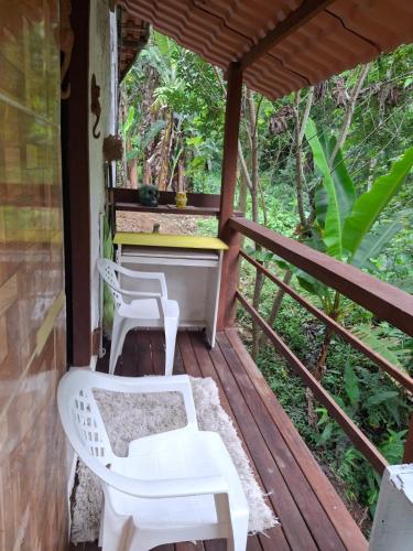 a porch with two white chairs and a piano at Pachamama suite no centro de Lumiar in Lumiar