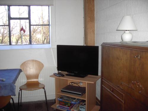 a room with a television on a table with a chair at Astrupgaard Farm Holiday in Skærbæk