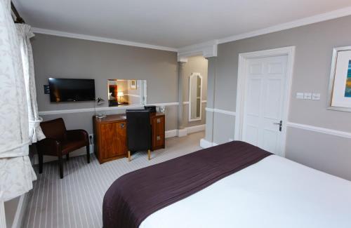a bedroom with a bed and a desk and a television at Hatton Court Hotel in Gloucester