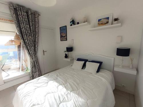 une chambre blanche avec un lit et une fenêtre dans l'établissement Bel appartement avec parking WIFI au centre-ville de PERROS-GUIREC - Réf 938, à Perros-Guirec