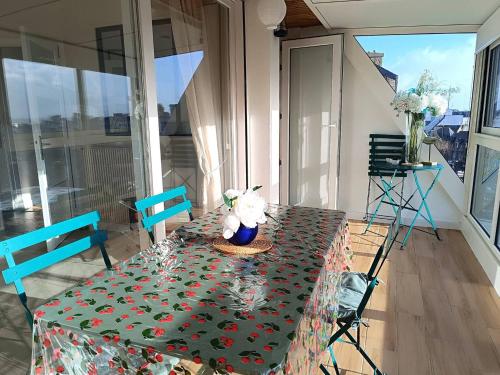 une table avec un tissu de table vert et des fleurs. dans l'établissement Bel appartement avec parking WIFI au centre-ville de PERROS-GUIREC - Réf 938, à Perros-Guirec