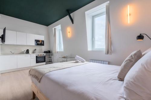 - une chambre blanche avec un grand lit et une cuisine dans l'établissement Studio équipé avec parking gratuit, à Villeneuve d'Ascq