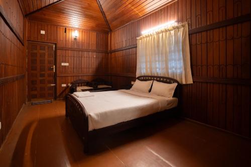 Casspo Forest Bungalow في Kallar Vattiyar: غرفة نوم بها سرير في غرفة بها نافذة