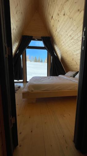a bed in a wooden room with a window at La Știubei Cabin in Mărişel