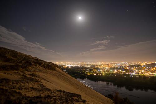 a view of a city at night with the moon at Anoosh camp in Aswan