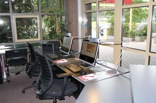 an office with two computers on a desk with chairs at Arvena Park Hotel in Nürnberg