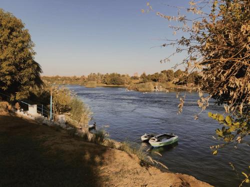 two boats are docked on a river at Anoosh camp in Aswan