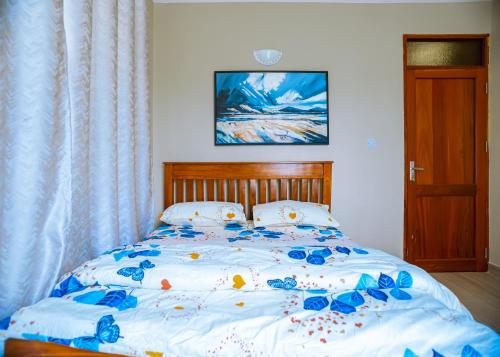 a bed with blue flowers on it in a bedroom at Juhudi Homes - Makongo in Dar es Salaam