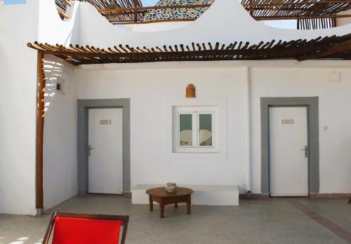 a white room with three doors and a table at La Maison des Vagues in Sidi Kaouki