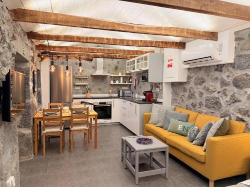 a living room with a yellow couch and a kitchen at Casa das Duas Ribeiras in Lajes do Pico