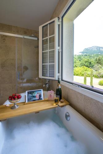 La salle de bains est pourvue d'une baignoire et d'une fenêtre. dans l'établissement Spacious villa in Tourrettes-sur-Loup with Private Lake access Sleep 16, à Tourrettes-sur-Loup