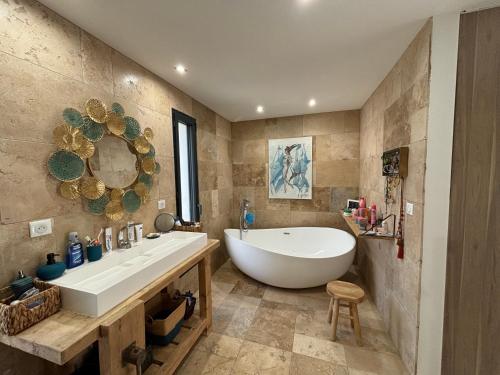 La salle de bains est pourvue d'une grande baignoire blanche et d'un lavabo. dans l'établissement Chez Marjorie et Nicolas, à Sallèles-dʼAude