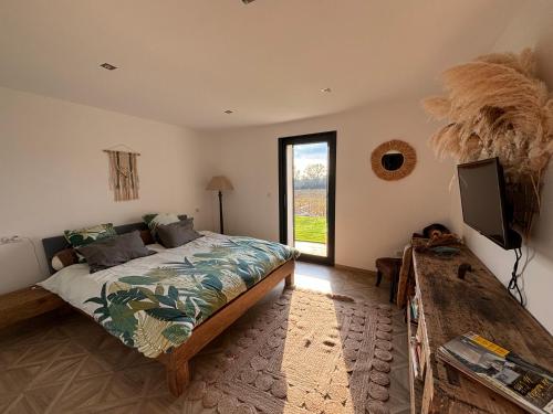 une chambre avec un lit, une télévision et une fenêtre dans l'établissement Chez Marjorie et Nicolas, à Sallèles-dʼAude