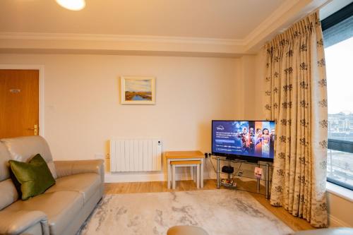 a living room with a couch and a flat screen tv at Dockside Penthouse - Free Parking in Galway