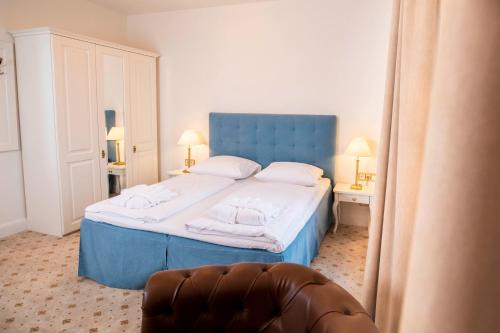a bedroom with a blue bed with towels on it at Hotel Villa Tripaldi in Schönberg in Holstein