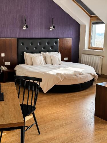 a bedroom with a large bed with a purple wall at Lawendowe Termy in Uniejow