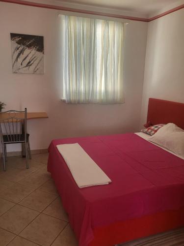 a bedroom with a red bed and a window at Apartments Mimoza in Slano