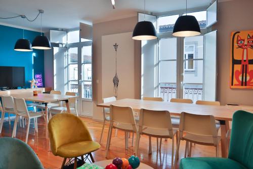 a dining room with tables and chairs and windows at Casa Gaea Stay in Braga