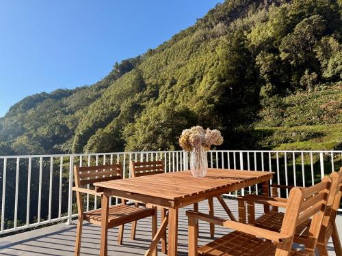 a wooden table with two chairs and a vase with flowers at Casa das Duas Ribeiras in Lajes do Pico
