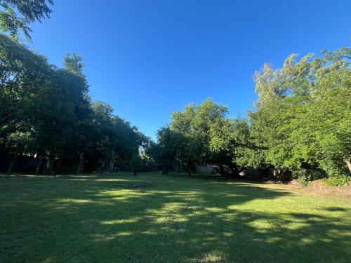 a large grass field with trees and a blue sky at Cuatro Estaciones in General Rodríguez