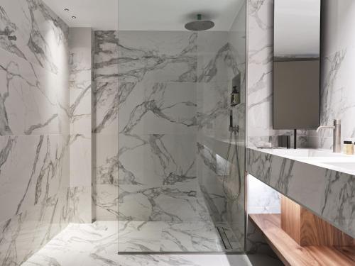 a bathroom with marble walls and a shower at Doryssa Seaside Resort in Pythagoreio