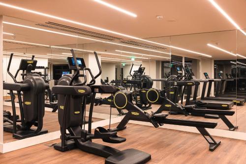 a gym with treadmills and ellipticals in front of a mirror at Doryssa Seaside Resort in Pythagoreio