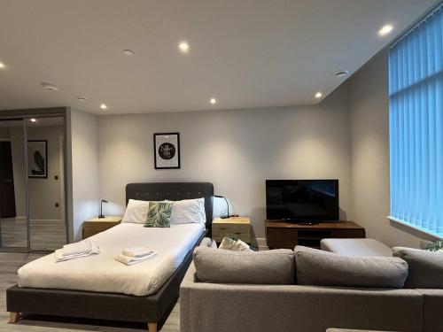 a bedroom with a bed and a couch and a tv at Modern Studio in Bracknell with free Parking in Bracknell
