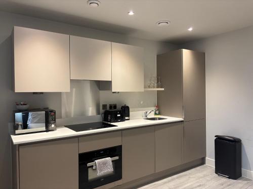 a kitchen with white cabinets and a microwave at Modern Studio in Bracknell with free Parking in Bracknell