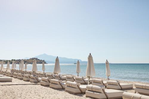 a row of chairs and umbrellas on a beach at Doryssa Seaside Resort in Pythagoreio