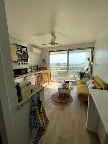 une cuisine et un salon avec une grande fenêtre dans l'établissement 2 pièces, cocon de charme, les pieds dans l'eau !, à La Grande Motte