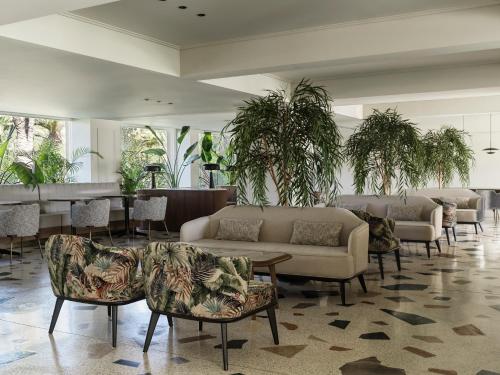a lobby with couches and tables and plants at Doryssa Seaside Resort in Pythagoreio