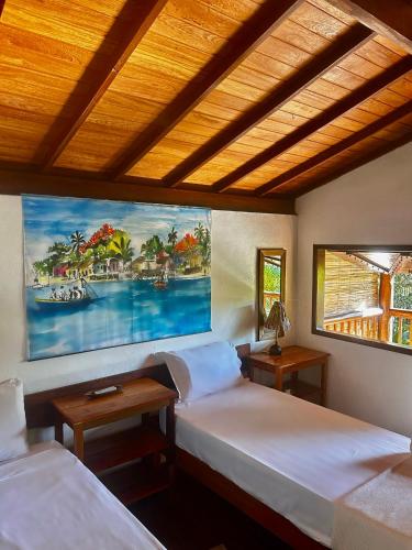 a room with two beds and a painting on the wall at Pousada Habitat Caraíva in Caraíva